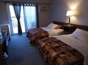 Habitación de hotel con 2 camas y ventana en Tobermory Inn & Suites, en Tobermory