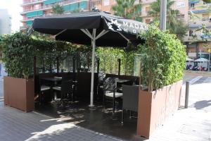 a restaurant with a black umbrella and tables and chairs at Hotel Madanis in Barcelona