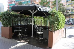 a patio area with a table, chairs and umbrellas at Hotel Madanis in Hospitalet de Llobregat