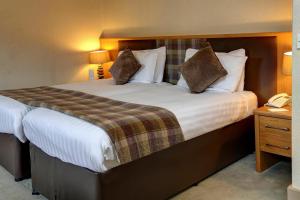 um quarto de hotel com uma cama grande e um telefone em Buchanan Arms Hotel & Leisure Club em Drymen