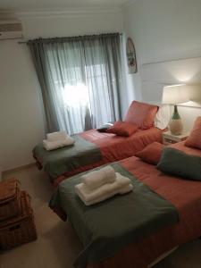 a room with three beds with towels on them at Apartamento de 2 Quartos no Centro de Monte Gordo in Monte Gordo