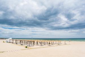 a beach with a row of umbrellas and the ocean at Apartamento de 2 Quartos no Centro de Monte Gordo in Monte Gordo