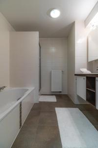 uma casa de banho branca com uma banheira e um lavatório em Laluna holiday apartment em Oostende