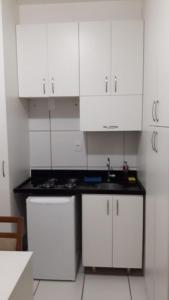 una cocina blanca con fregadero y armarios blancos en Park Studio, en Brasilia