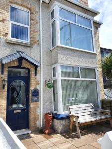 une maison avec une porte bleue et un banc en bois dans l'établissement Westward B&B, à Newquay