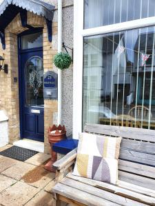 a wooden bench sitting outside of a house with a blue door at Westward B&B in Newquay