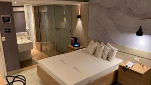 a bedroom with a large white bed and a shower at Sky Motel Itaqua in Itaquaquecetuba