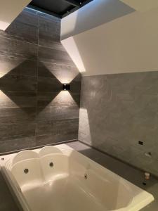 a white bath tub in a bathroom with a tile wall at Sky Motel Itaqua in Itaquaquecetuba
