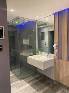 een badkamer met een wastafel en een glazen douche bij Sky Motel Itaqua in Itaquaquecetuba
