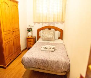 una piccola camera con letto e testiera in legno di New Go Inn a Madrid