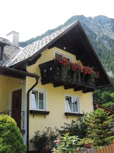 Casa amarilla con 2 ventanas con flores rojas en Grimmingapartment Maier, en Stainach