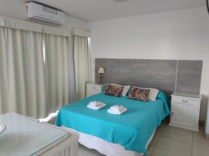 a bedroom with a blue bed with towels on it at Altos del Boulevard in Santiago del Estero