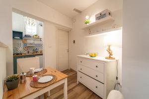 シラクーサにあるCasa Borbonica Cozy Apartment in Ortigia GROUND FLOORのキッチン、ダイニングルーム(テーブル、白いキャビネット付)