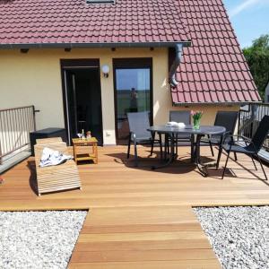 eine Holzterrasse mit einem Tisch und Stühlen auf einem Haus in der Unterkunft "Ferienwohnungen Wiesenblick" in Trassenheide