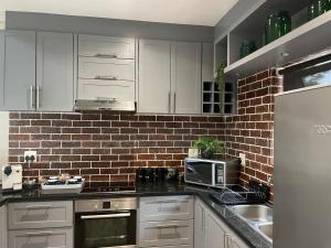 a kitchen with white cabinets and a brick wall at Oubaai Golf Estate in George