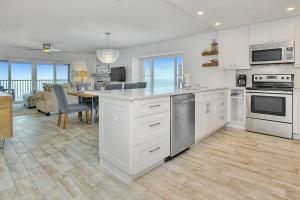 a kitchen with white cabinets and a dining room at Shore House 502 in Clearwater Beach