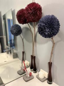 three purple flowers in vases on a bathroom counter at TENDANCE CAMPAGNE Chambre d'hôtes in Marillac