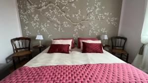 a bedroom with a large red bed with two chairs at TENDANCE CAMPAGNE Chambre d'hôtes in Marillac