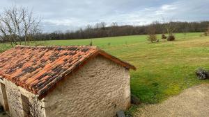 a building with a tile roof in a field at TENDANCE CAMPAGNE Chambre d'hôtes in Marillac