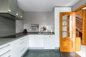 cocina con armarios blancos y puerta de madera en BeHouse Mairena, en Mairena del Aljarafe