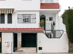 una casa blanca con una puerta negra en BeHouse Mairena, en Mairena del Aljarafe