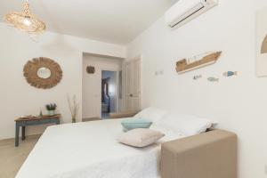 a white bedroom with a large bed and a table at Appartamenti Nonna Rosa in Santa Maria Navarrese