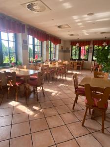 a restaurant with tables and chairs and windows at Müritz Landhotel Grüner Baum in Gotthun