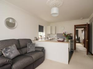 a living room with a couch and a kitchen at Shoreside Cottage in Wigton