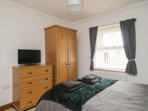 ein Schlafzimmer mit einem Bett, einer Kommode und einem TV in der Unterkunft Shoreside Cottage in Wigton