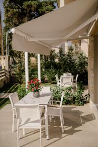 biały stół i krzesła pod białym parasolem w obiekcie casale w mieście Nikiti