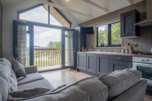 a living room with a couch and a kitchen at Cabin In The Woods - 1 Bedroom Lodge - Kilgetty in Stepaside