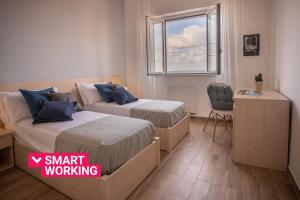 Dos camas en una habitación con ventana y silla. en Seaview Rooms in the center by Wonderful Italy, en Cefalú