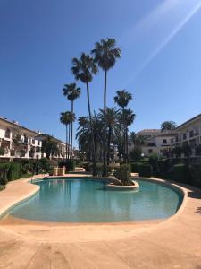 a swimming pool with palm trees in a resort at Apartamento de playa in Denia