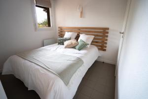 una camera da letto con un grande letto con lenzuola e cuscini bianchi di Chaleureux appartement à 500m de l’océan et 150m du Golf Moliets-Plage a Moliets-et-Maa