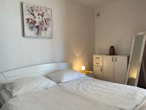 Un dormitorio con una cama blanca y una foto en la pared en APARTMENT YVONE en Zavalatica