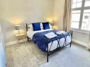 una camera da letto con un letto con cuscini blu e una finestra di The Balmoral close to the racecourse a York