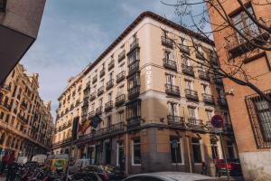 a large building on a city street with parked cars at Hotel Infantas by MIJ in Madrid