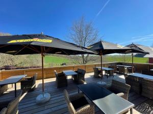 a deck with tables and chairs and umbrellas at Hôtel Restaurant Lamy in Troisvierges +55 photos