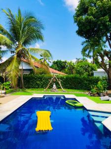 a pool with a yellow chair and palm trees at With Us Hotel by Coccoloba in Flandes