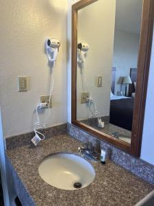 a bathroom counter with a sink and a mirror at Valley Motel in Alamosa