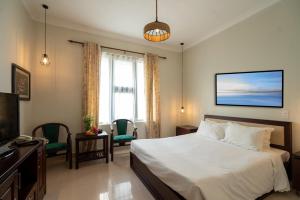 a hotel room with a bed and a television at Dana Pearl Riverside Condotel in Da Nang
