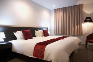 a bedroom with a large white bed with red pillows at Hakuba Grand Apartments in Hakuba +33 photos