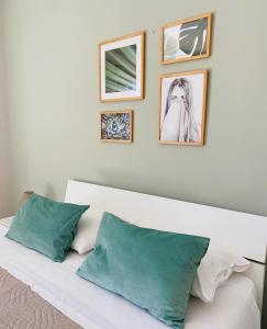 ジャルディーニ・ナクソスにあるVilla Valentinoの白いベッド1台、壁に4枚の写真が飾られたベッドルーム1室