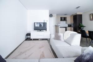 ein Wohnzimmer mit einem weißen Sofa und einem TV in der Unterkunft Laluna holiday apartment in Ostende