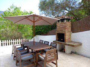 a wooden table and chairs with an umbrella on a patio at Villa Rosamar - Canyet de Mar in Cañet de Mar