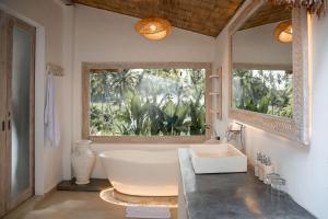 a bathroom with a large tub and a window at Hot Stone Club Ubud in Ubud
