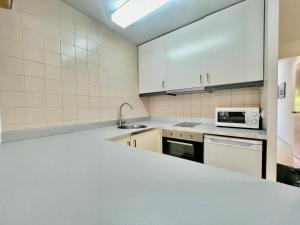 cocina con armarios blancos, fregadero y microondas en LOVELY LOFT IN SITGES by hlclub HUTB-11931 SOC, en Sitges