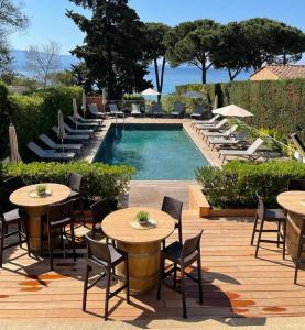 a pool with tables and chairs next to a resort at Hôtel La Pinède in Ajaccio