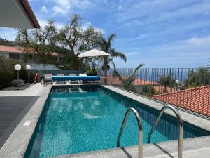 uma piscina com água azul em frente a um edifício em Vila Inês - Beautiful 2 bedroom villa with private pool and stunning views of the Atlantic Ocean em Arco da Calheta