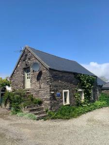 uma casa de pedra com um telhado preto em Ancaire Cottage Kilbronogue. Schull em Schull